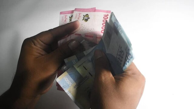 A man is counting 50 thousand and 100 thousand rupiah money