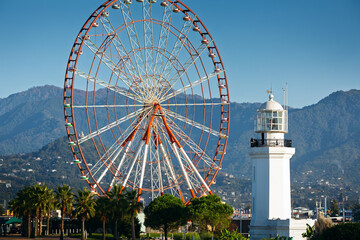 View of the observation wheel and lighthouse against a mountain backdrop in Batumi, Georgia