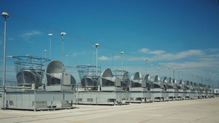 Fototapeta premium Industrial rooftop view featuring large HVAC ventilation and cooling systems under a clear blue sky, showcasing modern infrastructure and climate control technology in an urban commercial setting.