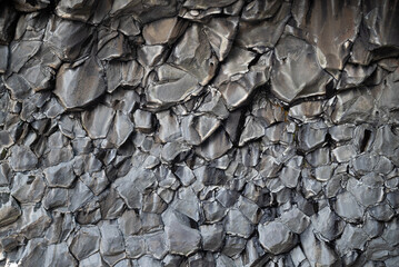 Background of dark basalt rock wall forming geometric pattern in nature