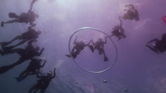 una aro de burbuja emerge por en medio de un grupo de buzos 