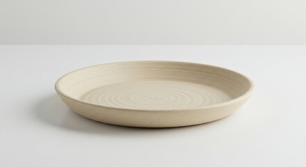 Minimalist Beige Ceramic Plate with Subtle Texture on Clean White Surface Still Life