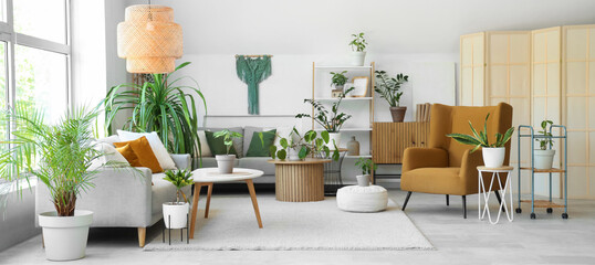 Interior of light living room with green houseplants, sofas and tables