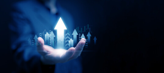 Business growth, economic development, or investment concept: A man holding upward pointing arrows alongside a graph representing success, progress, and increasing market performance