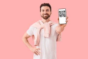 Happy bearded man holding smartphone with QR code on screen against pink background