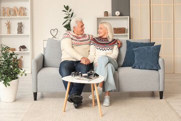 Happy mature couple sitting on sofa at home