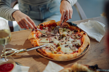 Woman cutting pizza with knife and fork in pizzeria