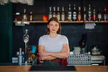 Bartender smiling with crossed arms behind bar counter