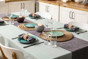 Table served for dinner with burning candles in kitchen. Closeup