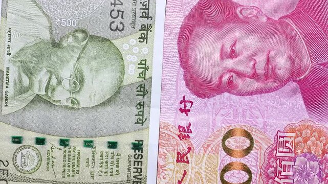 Close up view of rotating Chinese Yuan (CNY) and Indian rupee (INR) banknotes. Concept of  international commerce, financial partnerships, worldwide trade flows, emerging markets of China and India.