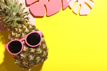 Composition with funny pineapple in sunglasses and decorative palm leaves on color background