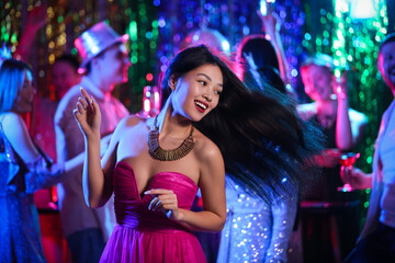 Young Asian woman dancing at party in night club