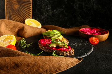 Sandwiches with tasty hummus, avocado and microgreen on dark table