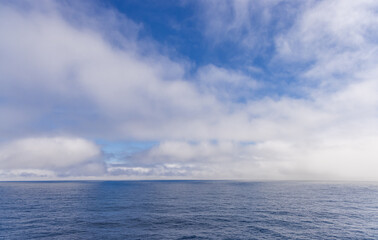Serene Ocean and Cloudscape Scene Under a Clear Blue Sky