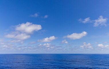 Obraz premium Scenic Ocean Horizon Under a Clear Blue Sky with Fluffy White Clouds
