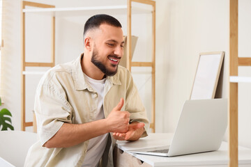 Young mute man using sign language during video call at home