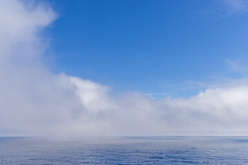 Bright Blue Sky with Ocean Horizon and Soft Clouds in the Distance