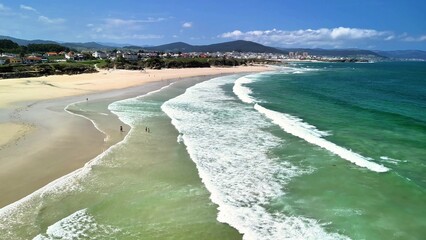 Behold this stunning aerial view of a peaceful beach featuring gentle waves and a clear blue sky