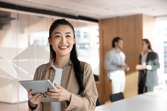 Asian businesswoman, marketing specialist, data analyst or female project manager holds tablet standing in modern corporate workspace. Business digital technology, innovations, and professional growth