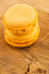 Delicious orange macarons stacked on a wooden table
