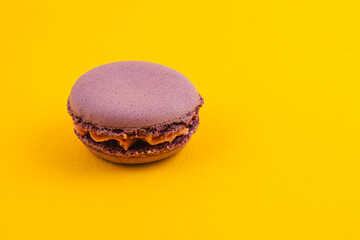 Purple macaron with creamy filling on yellow background