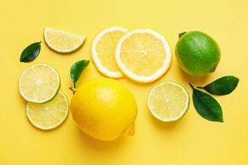 Fresh lemons, limes and green leaves on yellow background, flat lay