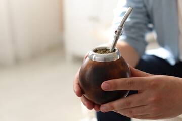 Man with traditional yerba mate tea at home, closeup. Space for text