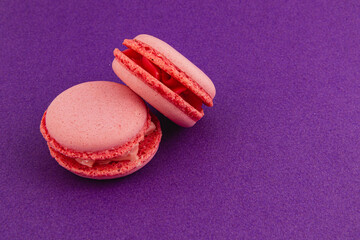 Pink macarons arranged on a vibrant purple background