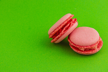 Delicate pink macarons on vibrant green background