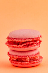 Delicious pink macarons stacked against an orange backdrop