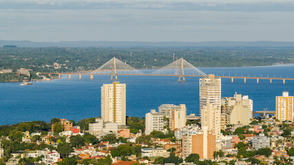 Daytime view of downtown Posadas, Argentina, with the San Roque González de Santa Cruz Bridge over the Paraná River in the background.