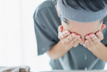 洗面所で顔を洗う若い男性