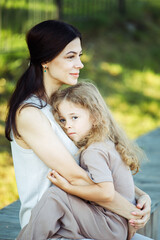 Naklejka premium Happy summer time. Little daughter hugging her young happy mom in the park.