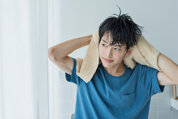 風呂上がりにタオルで髪を乾かす若い男性