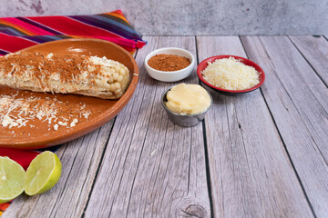A pair of corn cobs ready to be prepared with ingredients for preparing corn, lime, mayonnaise, cheese, and hot peppers. Mexican food.
