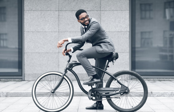 Keep calm and ride on. Businessman cycling against office buiding, going to work