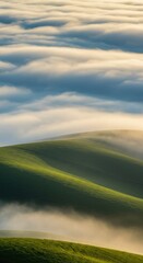 Obraz premium Rolling green hills meet a sea of fog under a partly cloudy sky, evoking tranquility and natural beauty. Serene and captivating landscape