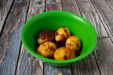 Spicy boiled eggs served in a green bowl with delicious chili sauce.