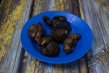 A traditional dish featuring fried chicken liver, served simply on a blue plastic plate.