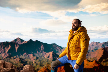 Determined climber pauses to admire the scenic view with mountains and a vast sky create a...