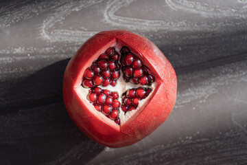 A fresh, juicy pomegranate fruit cut open, revealing its vibrant seeds