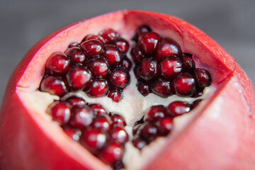 A macro shot of a ripe pomegranate bursting with juicy seeds. The fruit is cut open, showcasing its...