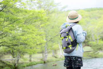 Naklejka premium 登山やトレッキングをする人 湖や景色を眺める顔無しの後ろ姿の女性 左にコピースペースあり