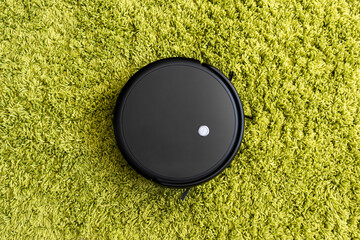 cleaning fleecy carpet with an automatic vacuum cleaner. Robot vacuum cleaner on floor, Smart...