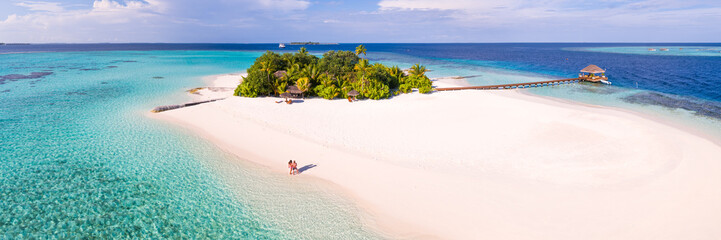 Aerial panoramic of couple on a beach on a small island in the Maldives