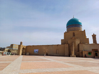 Fototapeta premium Kalon Mosque and the towering Kalyan Minaret in Bukhara, Uzbekistan. The mosque, with its large blue dome, stands adjacent to the minaret, a slender brick tower that dominates the blue skyline