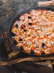 Seafood paella with shrimps, clams, and squid in a pan on fire