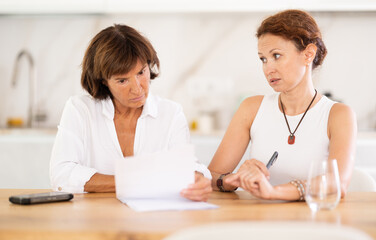 Obraz premium Two adult women discuss documents, try to solve financial problems