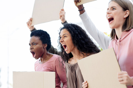 International group of young furious women with blank placards fighting against abuse. Female demonstrators protesting against women descrimination on the street, side view