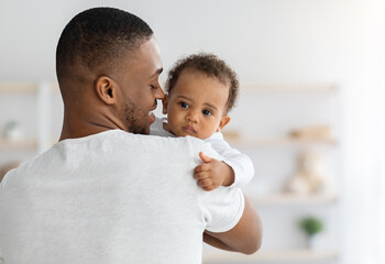 Father's love. Young afrian american dad holding his sweet infant baby in hands, closeup shot of caring black millenial dad spending time with cute adorable toddler child at home, copy space